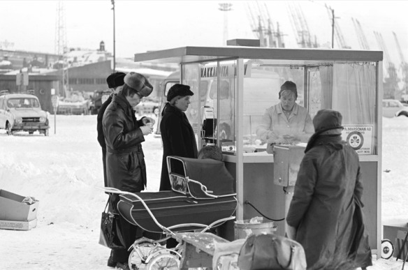 1970 . Ihmisiä makkarakojun ympärillä lumisella Kauppatorilla.