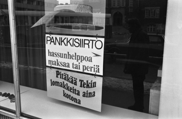1970 n. . Viides linja 10. Pankkisiirto - hassunhelppoa maksaa ja periä -mainos Osuuspankin ikkunassa Viidennellä linjalla Kalliossa.